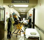 Medical crews move a patient on a hospital bed.