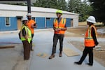 From left, Vancouver Homeless Response Manager Jamie Spinelli, Tapani Inc. Project Engineer Tyson Gregg, Vancouver Project Manager Kevin Kearns, and Vancouver Communications Director Laura Shepard at the construction site of what will be a 120-bed shelter for people experiencing homelessness, on July 15, 2026. 