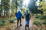 Jeannette Kempe-Ware, left, holds the hand of her husband, Gordon Ware, as they walk through Alberta Park in Portland during a dementia-friendly walk, Nov. 10, 2021. The pandemic has been particularly isolating for people with dementia and their families. The weekly walking group, in partnership with Oregon Walks, offers them a chance to connect.