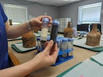 Curator Lily Carhart holds up different samples of liquid they extracted from a few dozen bottles.