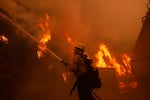 A firefighter battles the advancing Palisades Fire around a structure in the Pacific Palisades neighborhood of Los Angeles.