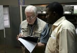 MAPUTO, MOZAMBIQUE: Former US President Jimmy Carter (L) takes notes 02 December 2004 while listening to a translater during his polling station observation visit in Maputo, Mozambique. Mozambique's long-time President Joaquim Chissano expressed surprise Thursday at the abysmal turn-out in elections to choose his successor, and blamed the poor showing on widespread illiteracy and ignorance of political systems. AFP PHOTO/MARCO LONGARI (Photo credit should read MARCO LONGARI/AFP via Getty Images)