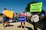 Trump supporters hold signs as they stand outside a rally for then-Vice President Kamala Harris in Milwaukee on August 20, 2024.