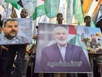 Demonstrators wave flags and hold pictures of the leader of the Palestinian militant Hamas group, Ismail Haniyeh, (C) and senior leader Saleh al-Arouri during a protest on July 31, 2024 in Beirut's Burj al-Barajneh camp for Palestinian refugees, denouncing his killing.