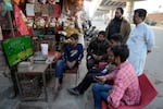 Cricket fans watch the ICC Champions Trophy cricket match between Pakistan and India on a television at a roadside shop in Lahore, Pakistan, Sunday, Feb. 23.