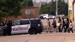 People raise their hands as they leave a shopping center following reports of a shooting, in Allen, Texas, on Saturday.