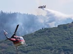 A CL 415 scooper, top, drops water on the Quarry Fire as a Firehawk helicopter maneuvers for a water drop Thursday, Aug. 1, 2024, southwest of Littleton, Colo. 