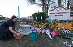 FILE - In this Feb. 14, 2019, file photo, Suzanne Devine Clark, an art teacher at Deerfield Beach Elementary School, places painted stones at a memorial outside Marjory Stoneman Douglas High School during the firstr anniversary of the school shooting in Parkland, Fla. It’s been more than 1,000 days since a gunman with an AR-15 rifle burst into a Florida high school, killing 17 people and wounding 17 others. And yet, with Valentine’s Day on Sunday, Feb. 14, 2021, marking the three-year milestone, Nikolas Cruz’s death penalty trial is in limbo.