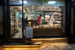 Customers and workers are seen through the window of Mahrouseh, a Syrian-owned sweet shop with packages of desserts on display.