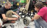 Oregon Spinal Cord Injury Connection and Shift Community Cycle volunteers looking into different possible fixes for a wheelchair in an undated provided image.