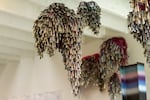 Inside Marie Watt’s artist studio in Portland, clusters of “Jingle Clouds” sculptures hang from the ceiling. Each sculpture is made with metal mixing bowls covered in hundreds of tin jingle cones, twill tape and mesh.