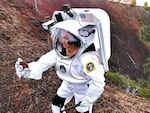 Spacesuit engineer Ashley Himmelmann in the Collins Aerospace spacesuit for analog studies examining and documenting a rock sample at Lava Butte via the spacesuit’s integrated Information Technologies and Informatics Subsystem.