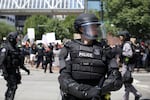 A Portland Police officer tries to keep right wing protesters and counter-demonstrators separate at dueling protests Aug. 4, 2018.