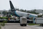 An Amazon cargo plane is seen after it crashed at Miami International Airport on Sunday in Miami. The Federal Aviation Administration said Prime Air Flight 7598 overran the runway while landing around 2 p.m. ET after departing from San Juan, Puerto Rico.