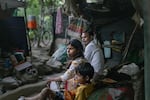 Kanchan and her son sit on his bed, next to Kamal, a relative, in the Muslim-majority neighborhood Bela Slum in New Delhi, India, October 13, 2026.