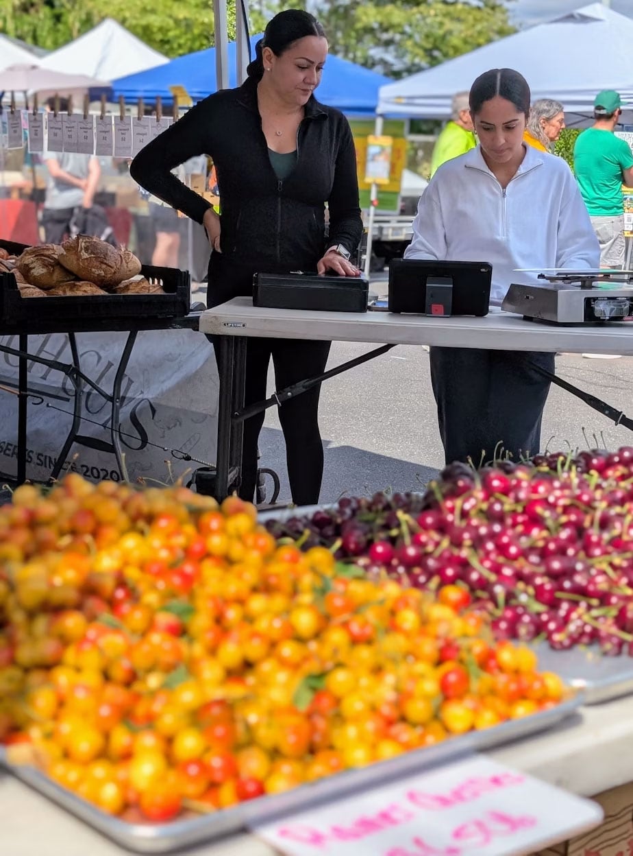 Blanca Gonzalez (left) and her associate sell cherries at a Seattle farmers market.