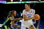 UCLA center Lauren Betts (51) looks to pass the ball while being guarded by Oregon forward Ehis Etute (35) during the first half of an NCAA college basketball game Sunday, Dec. 7, 2025, in Los Angeles.