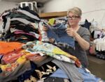 Julia Martin inspects some denim cutoffs at St. Vinnie's clothing warehouse in West Eugene in June 2026. Martin is the e-commerce sales manager and leads the "Upsmart" program.