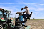 In this undated image provided by the High Desert Partnership, Christopher Bernau loads seeds on a tractor on the Burns Paiute Indian Reservation in Burns, Ore.