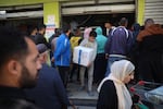 People queue to receive humanitarian aid, supplied by the World Food Program, in the Bureij refugee camp in the central Gaza Strip on November 18, 2024.