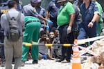 Illegal miners rescued from an abandoned gold mine sit on the floor as rescuers and South African Police Service (SAPS) officers record their details and provide assistance in Stilfontein on January 14, 2025.