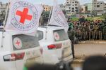 Hamas fighters stand guard as an International Red Cross vehicle arrives at the site of the handing over of two Israeli hostages in Rafah in the southern Gaza Strip, as part of the seventh hostage-prisoner release on February 22, 2025.