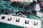 FILE - Phones are kept for charging at a Doctors Without Borders informal camp in Mardyck, northern France, Wednesday, July 2, 2025.