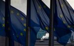 Smoke rises from a chimney behind E.U. flags fluttering in the wind outside E.U. headquarters in Brussels, Thursday, Dec. 24, 2020. European Union and British negotiators worked through the night and into Christmas Eve in the hopes of putting the finishing touches on a trade deal that should avert a chaotic economic break between the two sides on New Year's Day.