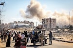 Smoke from a bombardment billows in the background as displaced Palestinians flee from Khan Younis, in southern Gaza, on Tuesday, Jan. 30.