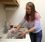 Mickey Moritz cleans a filter installed on her washing machine by PSU scientists, in Cannon Beach, Ore., on Nov. 13 2025.