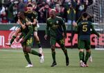Portland Timbers defender Larrys Mabiala, left, is mobbed by teammates after scoring a goal during the first half of an MLS soccer match against the Minnesota United in Portland, Ore., Sunday, Nov. 21, 2021.