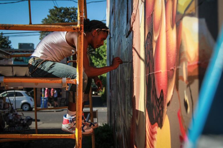 One of the artists commissioned to complete the mural paints details on the wall's midsection
