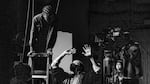 A film director gives direction an actress in a black and white photograph.