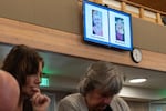 Donna Bishop left, prays with Leann Damian during a service at Victory Baptist Church, Oct. 18, 2026, in Bend, Ore., to honor the victims of the recent shooting at Silver Rail Elementary School. Images of Saylor Graham, 7, and Becky Drury, who were both injured in the shooting, are displayed on the screen.