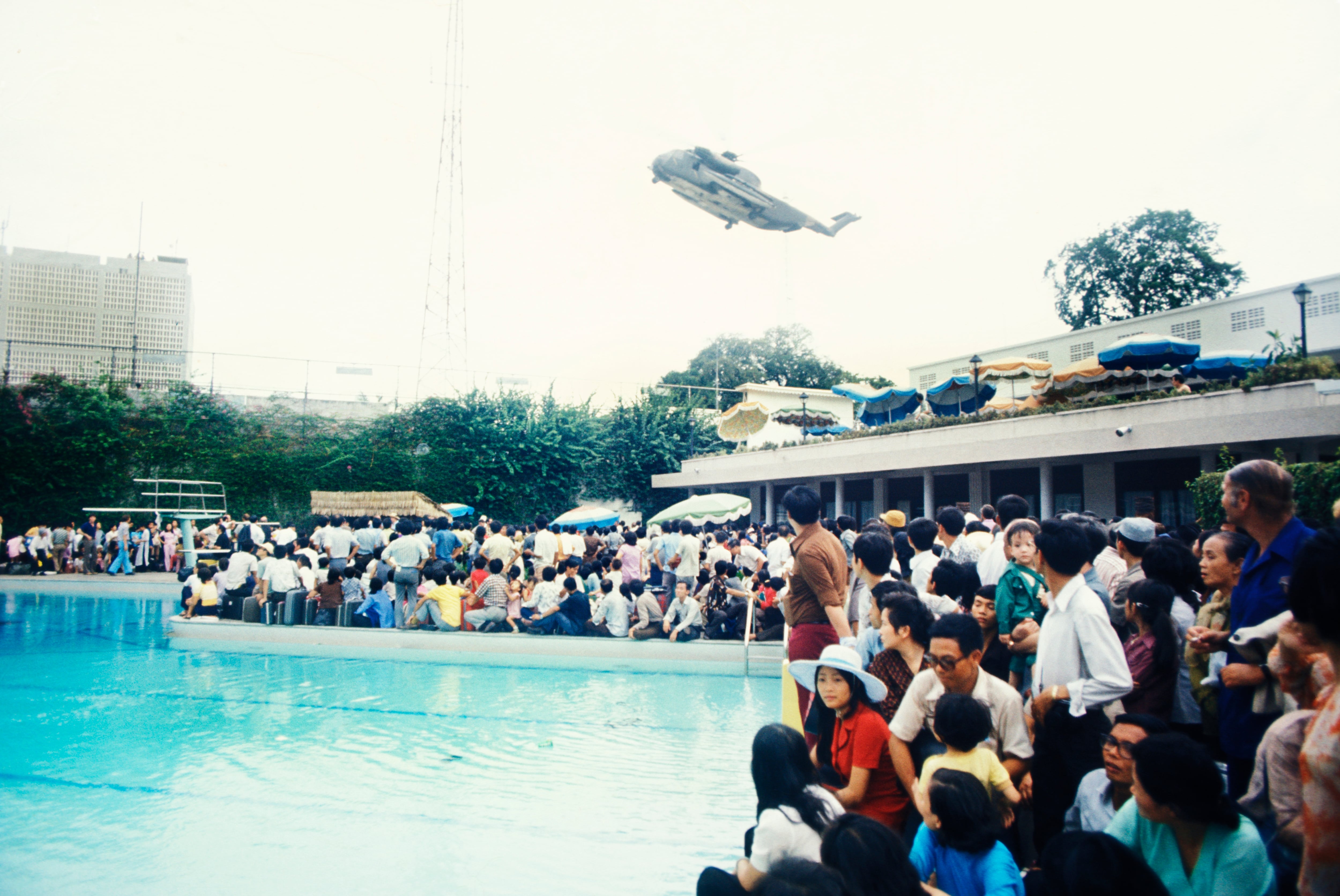 Evacuees inside the U.S. Embassy surround the embassy's swimming pool as a helicopter rescues stranded civilians trying to escape North Vietnamese troops about to capture Saigon in April 1975.