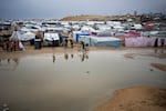 Palestinians displaced by the Israeli air and ground offensive in Gaza walk through a makeshift tent camp in Rafah on Jan. 27.