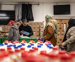 Team members at the No Limits Food Pantry distribution center pack recipient bags with fresh produce and can goods. 