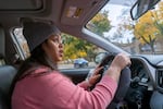 A woman with a toque and in a sweater is driving a car.