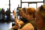 Two woman filming staring forward, filming with their phones.