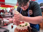 Chris Mortali puts the finishing touches on his mascarpone strawberry fraisier cake during the Big Portland Bake Show on June 27, 2026. The cake was decorated with the life cycle of a strawberry – going from flower to ripe strawberry – all with elements harvested from a friend’s backyard.