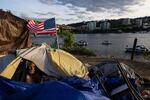 In this file photo from June 2021, a man experiencing homelessness sits in his tent in Portland, Ore., next to the Willamette River.