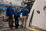 From left to right: Astronauts Jeremy Hansen, Artemis II mission specialist, Christina Koch, Artemis II mission specialist, and Reid Wiseman, Artemis II commander, pose for a portrait next to the Orion spacecraft mockup.