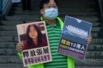 A pro-democracy activist holds placards with the picture of Chinese citizen journalist Zhang Zhan outside the Chinese central government's liaison office, in Hong Kong, Monday, Dec. 28, 2020. Zhang, a former lawyer and citizen journalist from Shanghai, has been sentenced to four years in prison for her reporting on the initial coronavirus outbreak in Wuhan, China. The activists demand the releases of Zhang, as well as the 12 Hong Kong activists detained at sea by Chinese authorities.