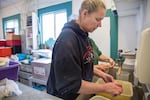 Tina Ward, co-owner of Sportsmen's Cannery, cleans buckets of razor clams dropped off by customers.