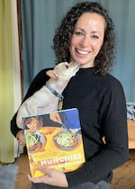 Farideh Sadeghin holds a very adorable dog and her cookbook, "Munchies Guide to Dinner."