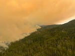 Smoke billows from a hillside Wednesday, July 19, 2023, as the Flat Fire continues to spread in the Rogue River-Siskiyou National Forest between Gold Beach and Grants Pass. The fire started near Oak Flat Campground along the Illinois River and now threatens the small community of Agness.