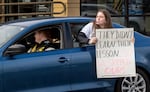 A student holds a sign during a protest outside St. Helen's High School on Nov. 15, 2024. Dozens of students and parents have protested for two days, after two teachers were arrested for allegedly sexually assaulting students.