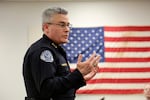 A man in a Vancouver Police Department uniform stands in front of a U.S. flag.