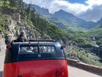 Along Glacier National Park's Going to the Sun Road, tourists admire the view from one of the park’s vintage red buses