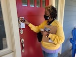 A CROWN Act campaign leader sticks a "Know Your Rights" guide in a door during a canvassing event in Portland on Oct. 30, 2021.